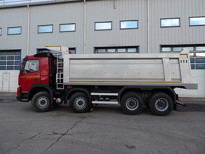 En röd lastbil med en silvrig tipperpåbyggnad