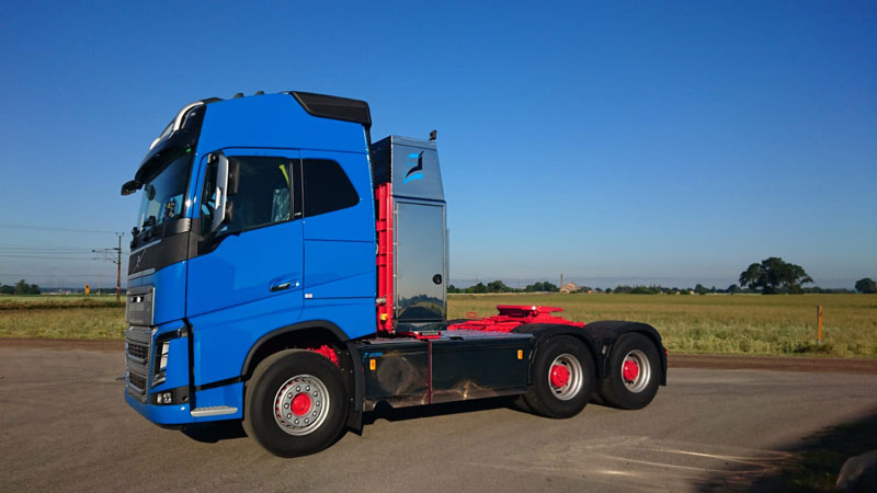 Baksidan av en blå lastbil mot en röd byggnad